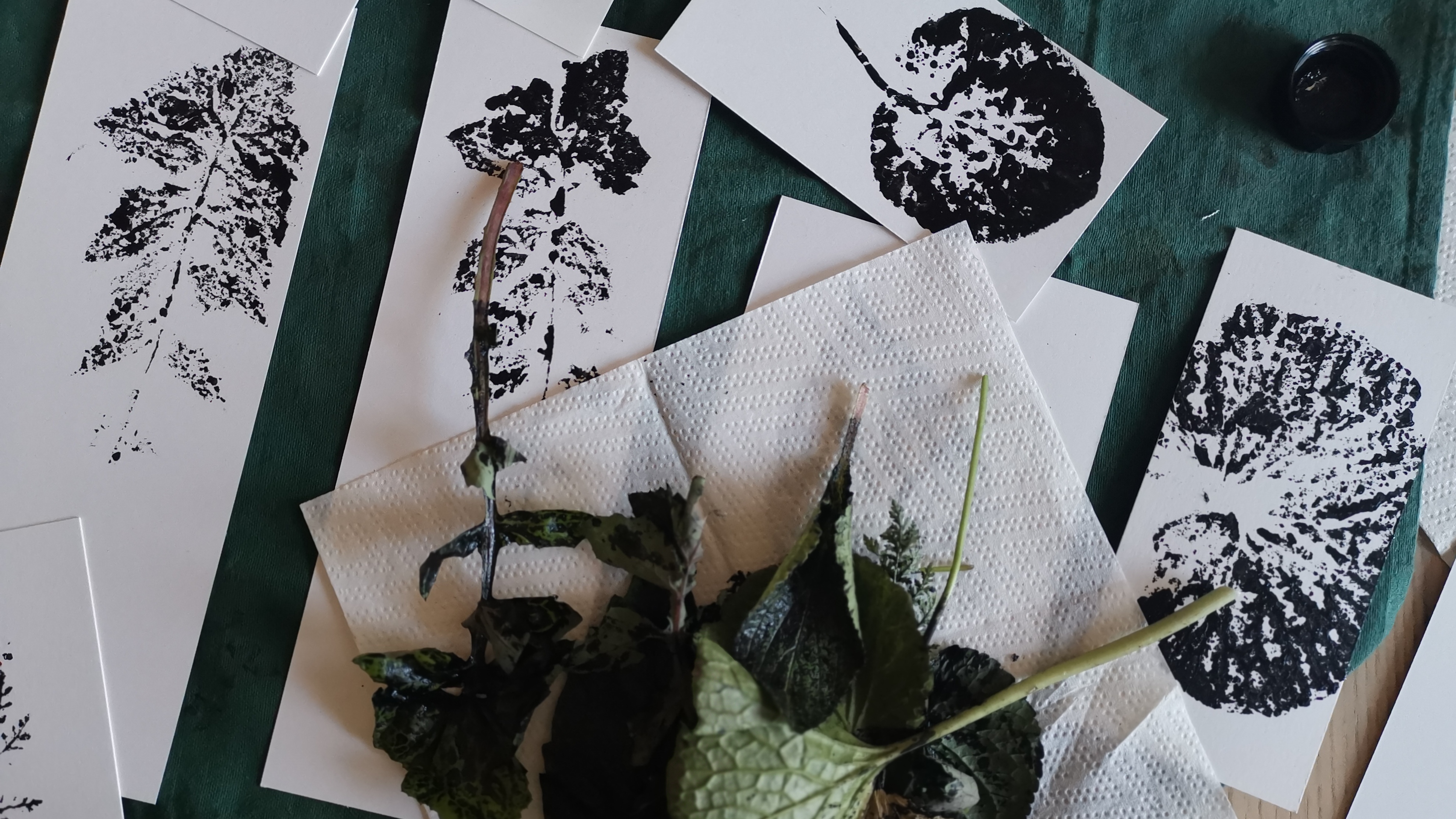 Des estampes de feuilles de pissenlit, violettes et wasabi à l'encre,
posées sur un plan de travail avec les feuilles fraîches qui viennent d'être
utilisées