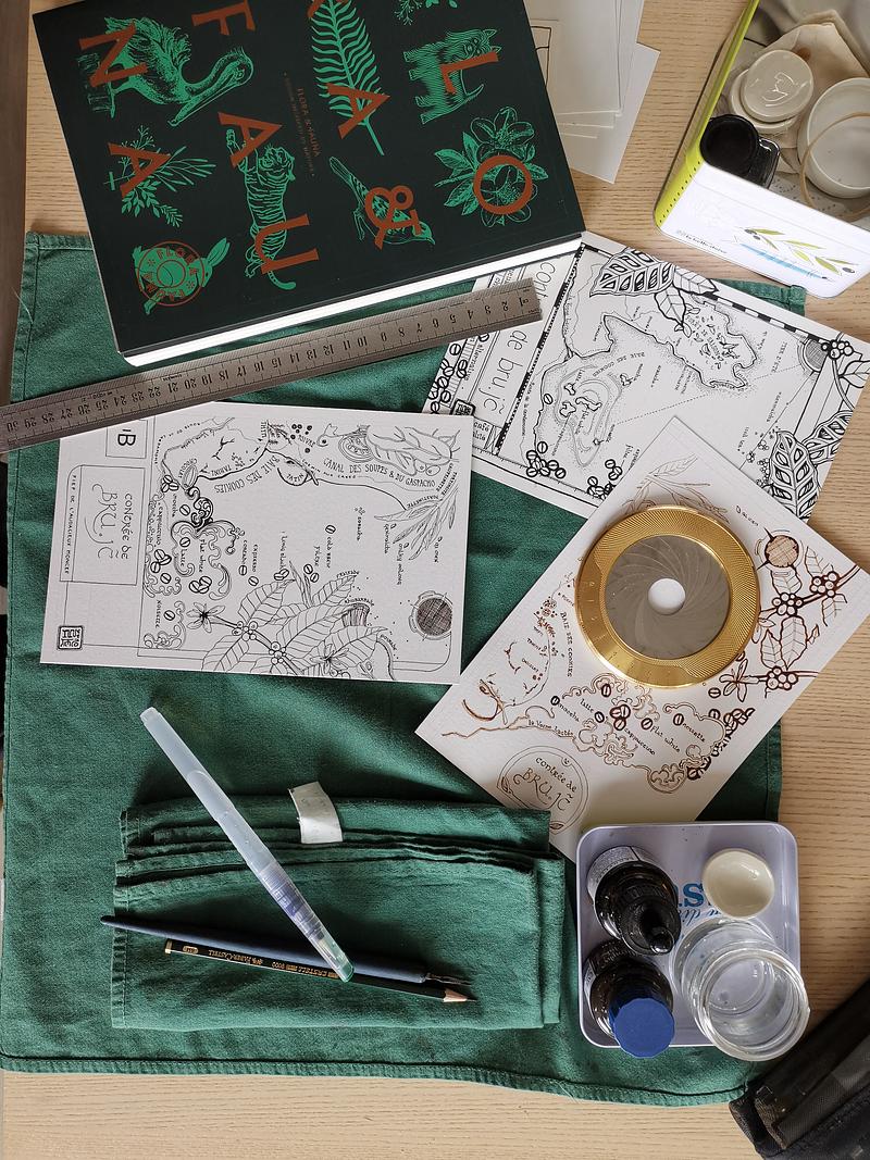 Une table de travail vue du dessus avec des croquis de carte, un trace-cercle
et du matériel d'ilustration