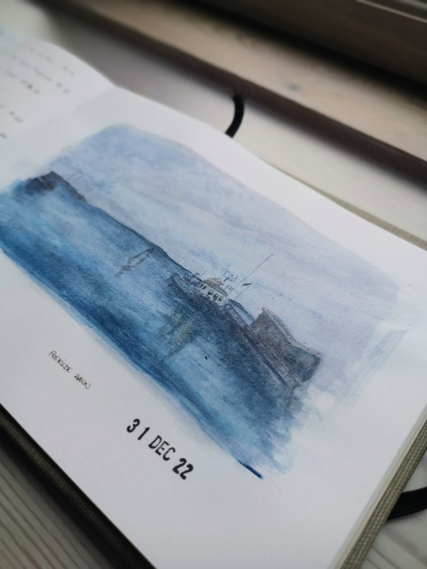 Gros plan sur une illustration à l'aquarelle représentant une étendue d'eau
avec une jetée à droite, le long de laquelle est amarré un bateau. Les
tonalités de l'illustration sont dans les bleus et violets et inpirent la nuit
tombante.
